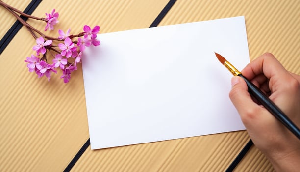 A person holding a brush and a piece of paper with a flower photo