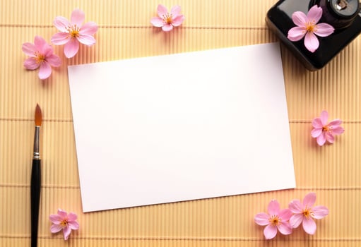 A blank sheet of paper, a pen and a paintbrush on a bamboo mat photo