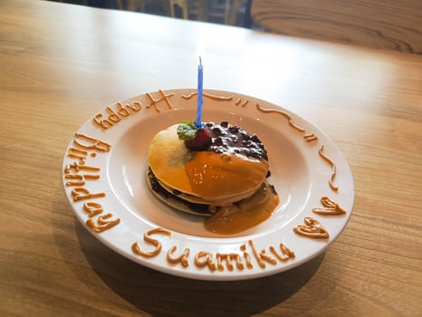 Festive Pancakes with Birthday Candle on Plate with Caramel Decoration photo