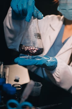 A woman in a lab coat is holding a beaker photo