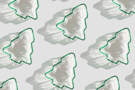 Minimal pattern Green color glass form as New Year trees, Christmas fir at sunlight with beautiful shadows and sparkling sun glare on white background. Winter holiday concept, aesthetic trends photo