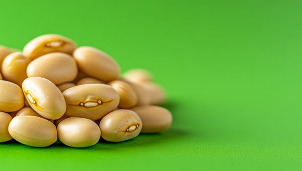 Fresh beans on green. A pile of light-colored beans rests on a vivid green surface, showcasing their smooth texture and natural sheen. photo
