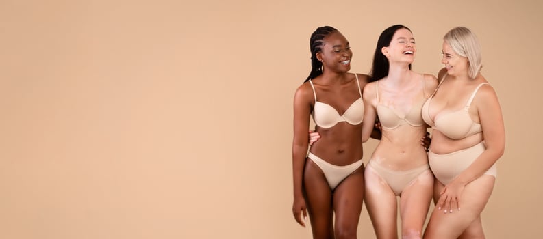 Portrait Of Body Positive Women Of Different Nationalities And Weight Types Posing On Beige Background, Full Length Shot Of Beautiful Black Female, Plus Size Woman, And Lady With Vitiligo In Underwear photo