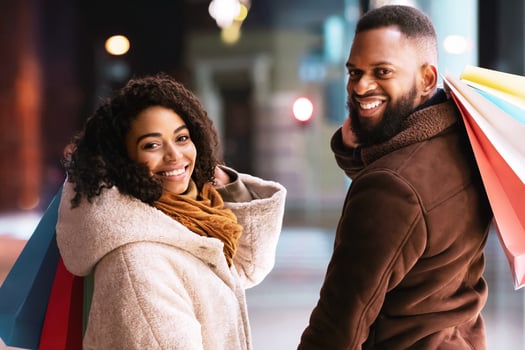 Happy Loving Family. Portrait of smiling black man and woman turning back and looking at camera over the shoulder holding hands, carrying shopping bags. Cheerful african american couple near mall photo