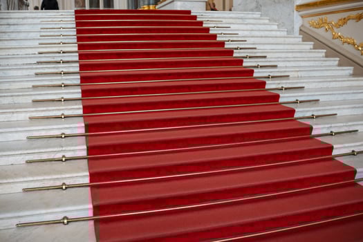 Red Carpet Lined Staircase in Opulent Building With Striking Architectural Details and Elegant Ambiance During a Formal Event photo
