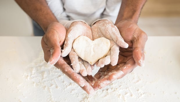 Happy childhood concept. Black man palms holding child palms with heart shaped cookie, panorama photo