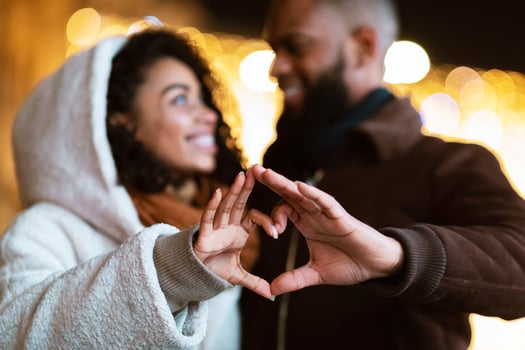 Love, Affection And Bonding Concept. Closeup outdoor portrait of happy smiling black african american couple making heart shape with hands walking together in the evening, looking at each other photo