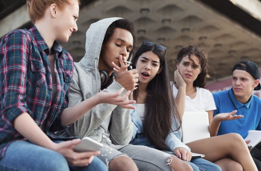 Black teen guy smoking cigarette, his friends judging him. Social issues between young people photo