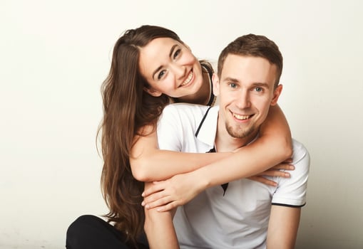 Happy man carrying his girlfriend on back. Young couple having fun together, posing and looking at camera photo