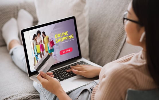 Online Shopping Concept. Back view of asian girl using laptop, looking at website, holding credit card, sitting at home photo
