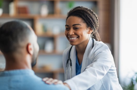 Cheerful attractive young african american woman doctor touching unrecognizable eastern man patient shoulder, general practitioner happy with results of treatment, supporting her patient, closeup photo