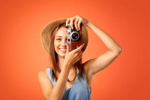 Cheerful girl photographer taking photos over yellow studio background