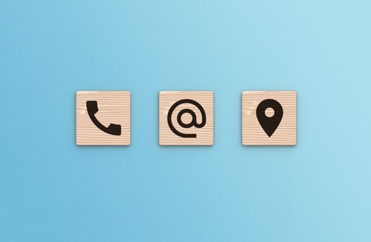 Contact Us concept. Telephone, envelope letter and location icons on wooden blocks on blue background photo