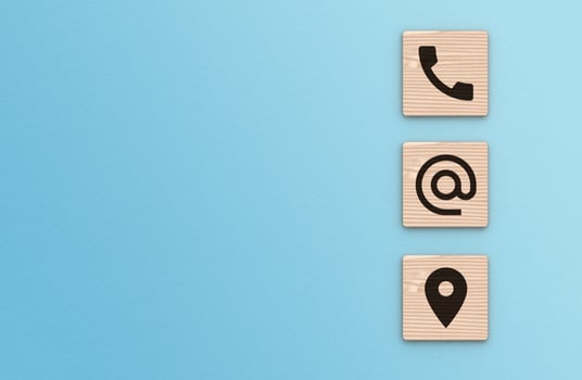 Contact Us background. Telephone, envelope letter and location icons on wooden blocks with copy space blue background photo