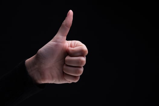 Hand of man showing thumb up gesture on black background. Sign fingers Like photo
