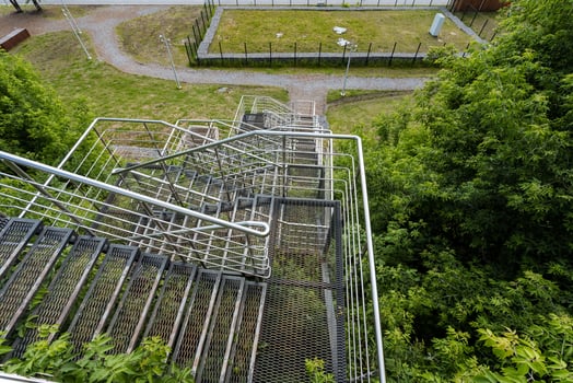 This image captures an aerial view showcasing a fire escape that is beautifully surrounded by a lush landscape of trees and green grass, creating a striking visual contrast photo