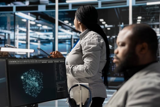 Data center employee monitoring system performance using PC, identifying malfunctions. African american server farm IT expert troubleshooting computer bugs, implementing optimizations photo