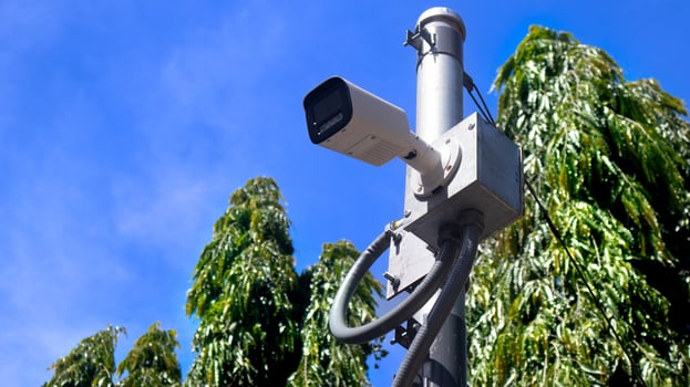 CCTV cameras on a metal box for outdoor installation. Attached to the steel pole structure. Background of Polyalthia longifolia or Asoke tree name in Thailand under blue sky. photo