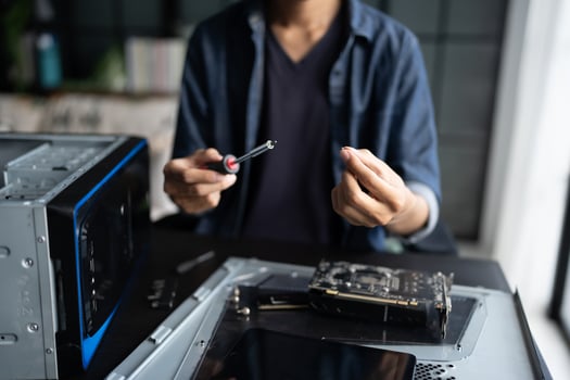 a man is working on a computer with a screwdriver. photo