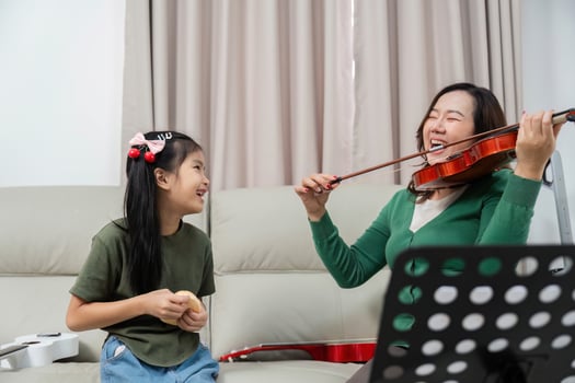 Joyful Music Practice. Child and mother enjoying violin lessons at home. photo