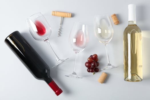 Flat lay. Grapes, corkscrew, bottles and glasses with wine on grey background photo