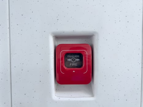 Red fire alarm emergency button mounted on modern speckled wall. Safety equipment detail for use in case of fire, essential in public transportation and commercial buildings photo
