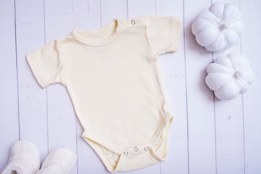Yellow baby bodysuit mockup for logo, text or design on wooden background with pumpkins photo