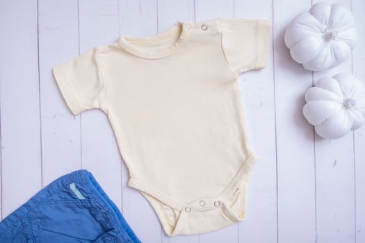 Yellow baby bodysuit mockup for logo, text or design on wooden background with pumpkins top view photo