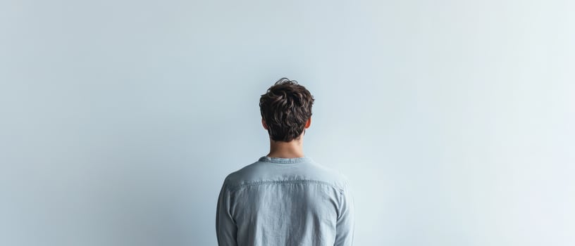 Person standing alone in front of blank wall photo