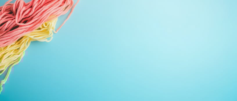 Colorful yarn strands on a light blue background photo