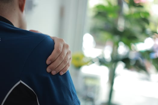 a man with a shoulder pain in a blue shirt photo