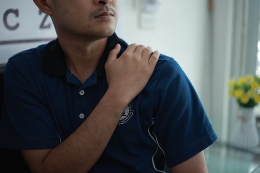 a man in a blue shirt holding his shoulder photo