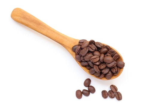 Brown roasted coffee beans in a wooden spoon on a white background photo