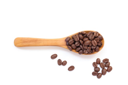 Brown roasted coffee beans on a wooden spoon on a white background photo