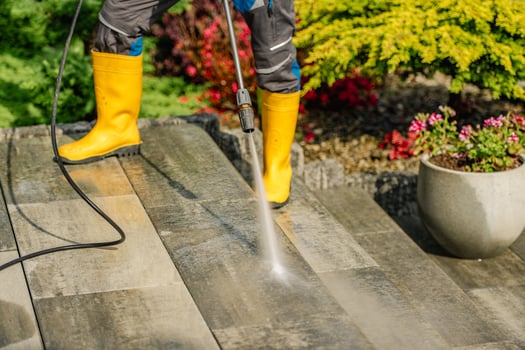 Pressure Washing Outdoor Patio in Bright Sunlight With Vibrant Garden Backdrop photo