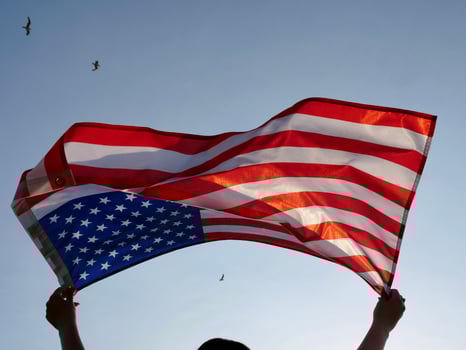 A man holds an american flag in front of a plane flying over the us flag photo