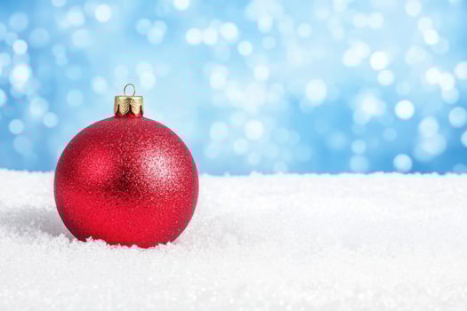 Sparkling Red Christmas Ornament on Snow with Blue Background photo