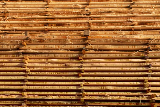 Stacks of bamboo poles are organized horizontally, showcasing their natural texture and color, ideal for eco-friendly construction photo