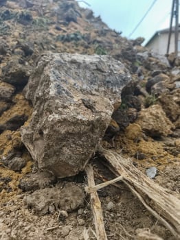 A large rock sits on top of a pile of dirt. The dirt is brown and the rock is gray photo