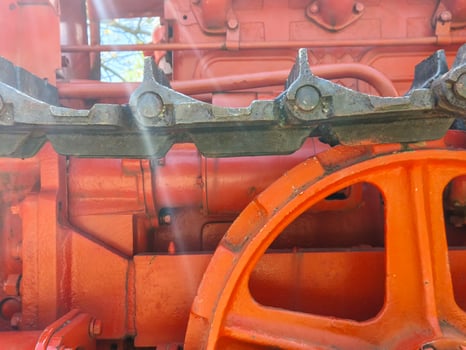 The front of a red tractor with a black wheel. The wheel is orange and has a black rim photo