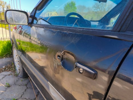 A black car with a broken door handle. The car is parked in a parking lot photo