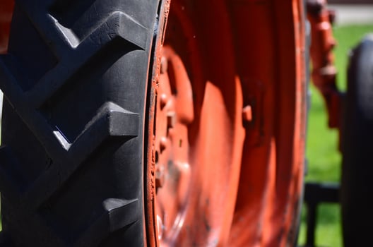 A red and black tractor tire with a black rim. The tire is the main focus of the image, and it is clear that it is a tire on a tractor photo