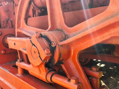 The red wheel is rusty and has a lot of bolts. It is old and worn out. The image has a vintage feel to it photo