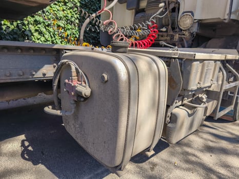 A dirty truck engine with a red and white hose attached to it. The hose is positioned on the side of the engine and is connected to a red and white container photo