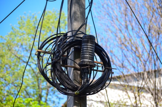 A black wire is wrapped around a pole. The wire is tangled and twisted. The sky is blue and clear photo