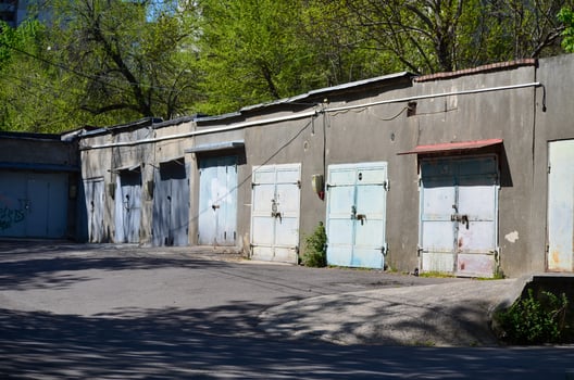 A row of old blue doors sit in front of a building. The building is old and has a rustic appearance. The doors are open and the building is empty photo