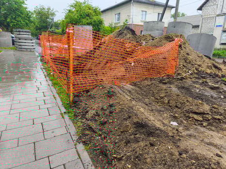 A construction site with orange fencing and a pile of dirt. The fence is orange and the dirt is brown photo