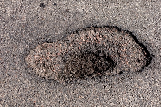 Large hole in the asphalt is evident on the highway, indicating significant damage that requires urgent repair to ensure safety for all vehicles photo