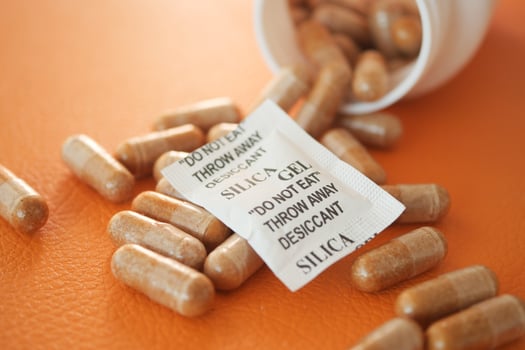 Silica gel packet and capsules on orange surface photo