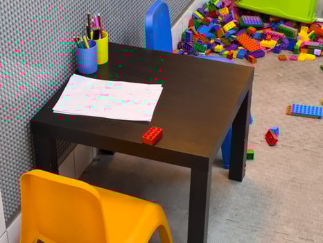 A vibrant workspace features a small table with papers and pens, surrounded by a colorful mess of building blocks on the floor photo
